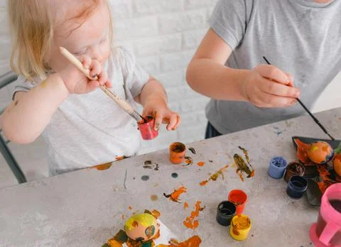 Two children paint eggs in the kitchen on the eve of the Easter holiday Stock Photos