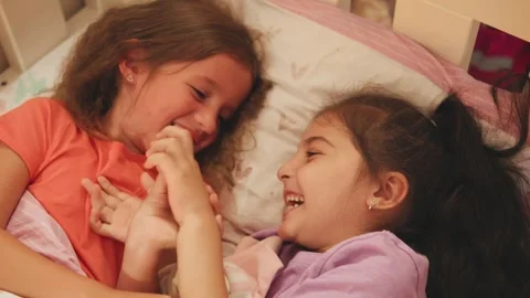 Two children play and laugh together in bed during a cozy evening at home Stock Footage 330750044