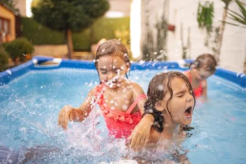 Two children play in a backyard pool on a sunny summer afternoon Stock Photos
