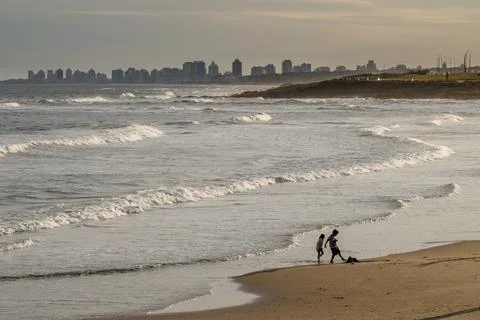 Two children play on the beach, with the Punta del Este skyline in the back.. Stock Photos