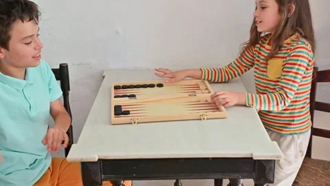 Two children playing backgammon and laughing together Stock Footage 290050488