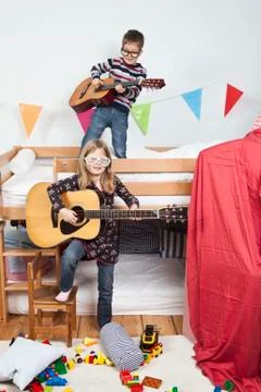 Two children playing with guitars in a child's playroom Stock Photos
