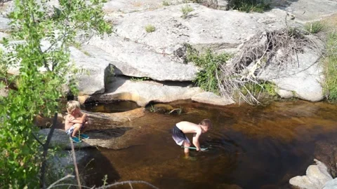Two children playing in a natural pool in summer Stock Footage 277101313