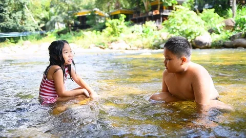 Two children playing put rock into water at the river. Stock Footage 119405887