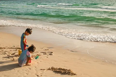 Two Children Playing in Sand at the Beach Edge Stock-Fotos