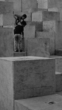 Two children playing in a small square with concrete block sculpture, the 스톡 사진