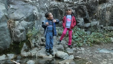 Two children pose for a photo while standing near a rock. Stock Footage 163946056