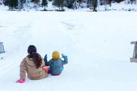 Two children preparing to slide down the snow hill Stock Photos
