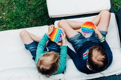 Two children push on pop it on sofa on terrace Foto stock