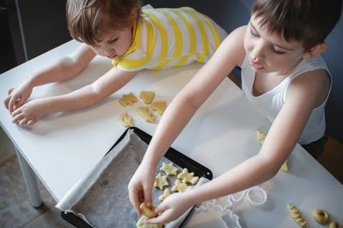 Two children put cookies on a baking sheet. homemade desserts. The view from  Foto stock