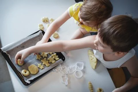 Two children put cookies on a baking sheet. homemade desserts. The view from  Stock Photos