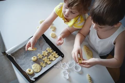 Two children put cookies on a baking sheet. homemade desserts. The view from  Stock Photos
