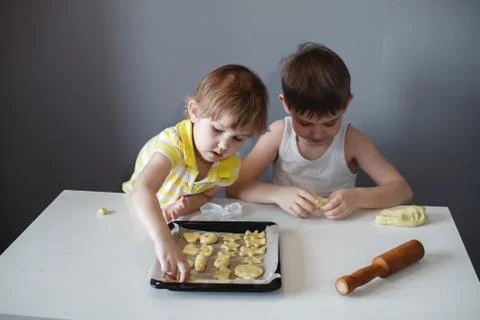 Two children put cookies on a baking sheet. homemade desserts. Stock Photos