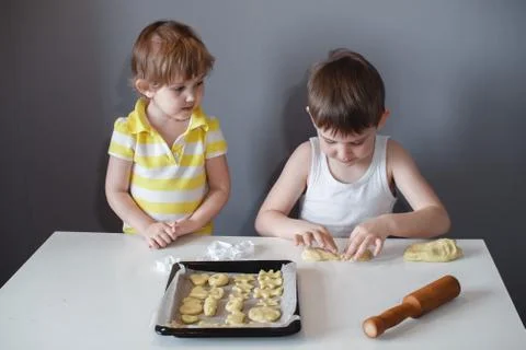 Two children put cookies on a baking sheet. homemade desserts. Stock Photos
