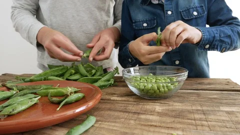 Two children removing peas from their pods Stock Footage 129707110