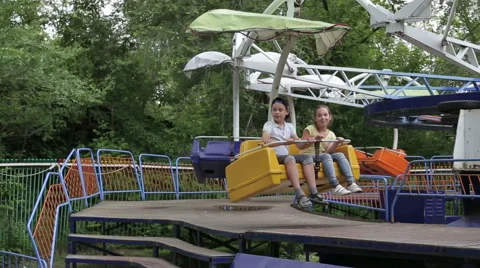 Two children ride on the carousel in an amusement park Stock Footage 65399162