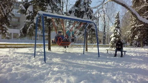 Two children ride on a swing. The boy is sitting on the bench. Video stock 88243056
