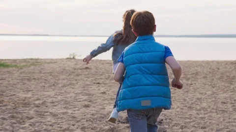 Two children run along sandy beach to seashore Stock Footage 108651590