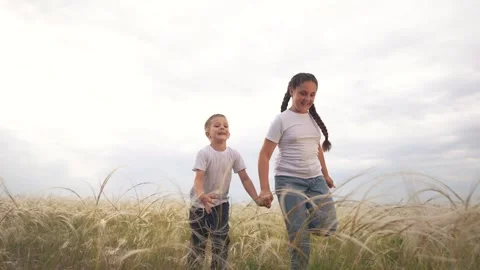 Two children running through a field. Children running in a field outdoors with Stock Footage 318010814