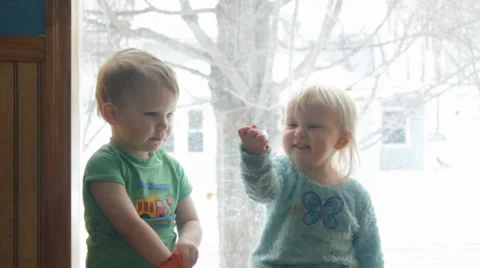 Two children share a snack in front of a winter window Stock Footage 35801385