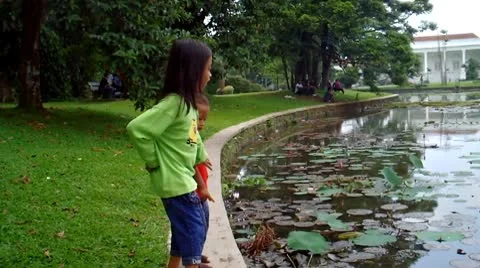 Two Children at The Side of a Pond Stock Footage 10678490