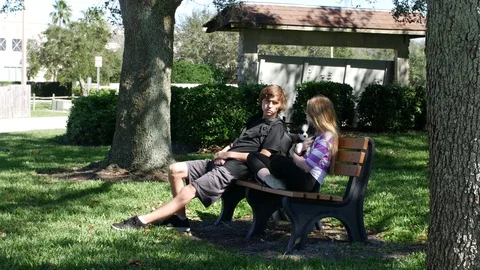 Two children sit on a park bench enjoying the day Stock Footage 71776871
