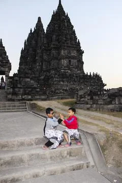Two children sit on stone steps, smiling at each other Stock Photos