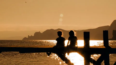 Two Children Sitting On Bridge At Sunset Stock Footage 47570755