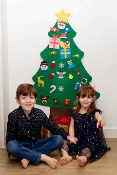 Two children sitting in the floor in front of a Christmas tree Stock Photos