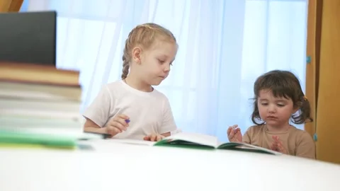 Two children sitting at table with laptop. Group of children are doing remote Video stock 316604424