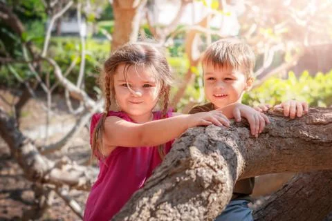 Two children smite on tree trunks Stock Photos