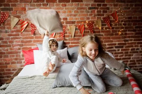 Two children in soft pyjamas have arranged fight by pillows. Stock Photos