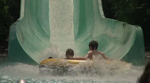 Two Children Speeding Down a Water Slide in a Tube into the Pool Stock Footage 24691224