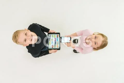 The two children stand with devices. View from above Stock Photos