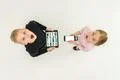 The two children stand with devices. View from above Photo