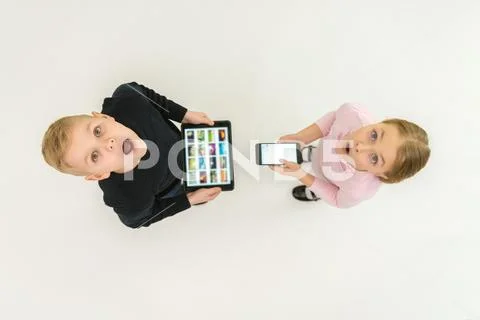 The two children stand with devices. View from above Stock Photos