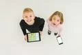 The two children stand with devices. View from above Photo