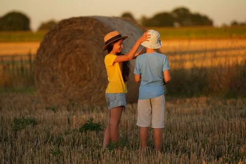 Two children stand in front of a haystack, a girl in a Mexican hat sideways, a Stock Photos