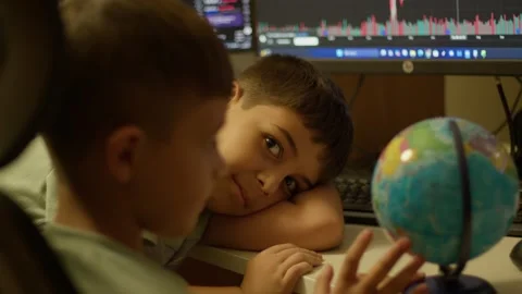 Two children study geography with a globe and computer screens 動画素材 347533658