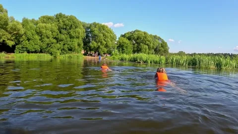 Two children swim joyfully by the river, ensuring safe fun Video stock 283086992
