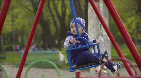 Two children on swing in spring park Stock Footage 62500476