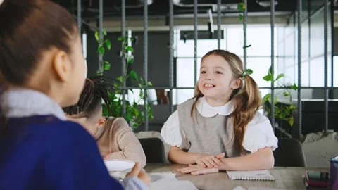 Two children talk in a modern room with plants while one girl smiles and holds a Stock Footage 331307325