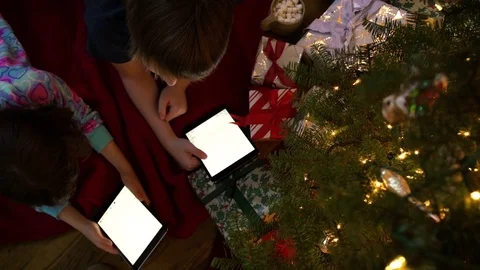 Two children using tablets under a Christmas tree 動画素材 76237593