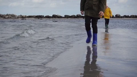 Two children walking along the Baltic sea coast in rubber boots. Slow motion. Stock Footage 125568942