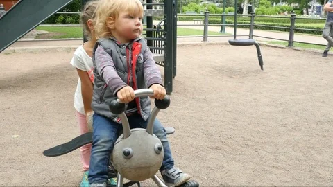 Two children walking on playground and swinging on big swing set Stock Footage 80909479