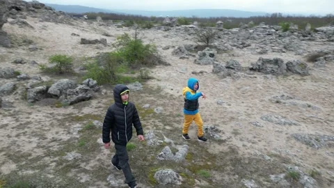 Two children walking through rocky landscape and limestone formations. Outdoor Stock Footage 324879556