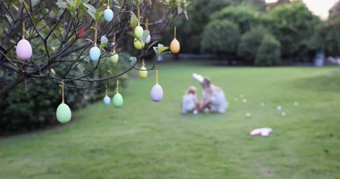 Two Children Wearing Bunny Ears when Pick Up painted Easter Egg Hunt In Garden Stock Footage 229786571