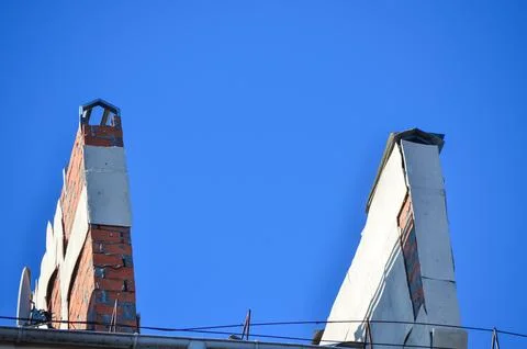 Two chimneys on a building with a blue sky in the background.  Stock Photos