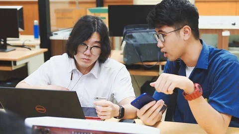 Two Chinese computer engineering student discussing in a computer class Stock Footage 107372343