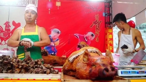 Two Chinese men with bare arms selling roast pigs Stock Footage 71219280